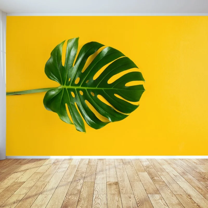 Wall mural monstera leaf on vibrant yellow background