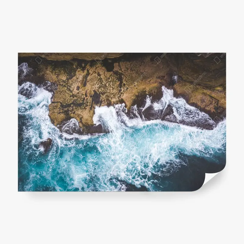 Wall mural turquoise surf over rocky coastline